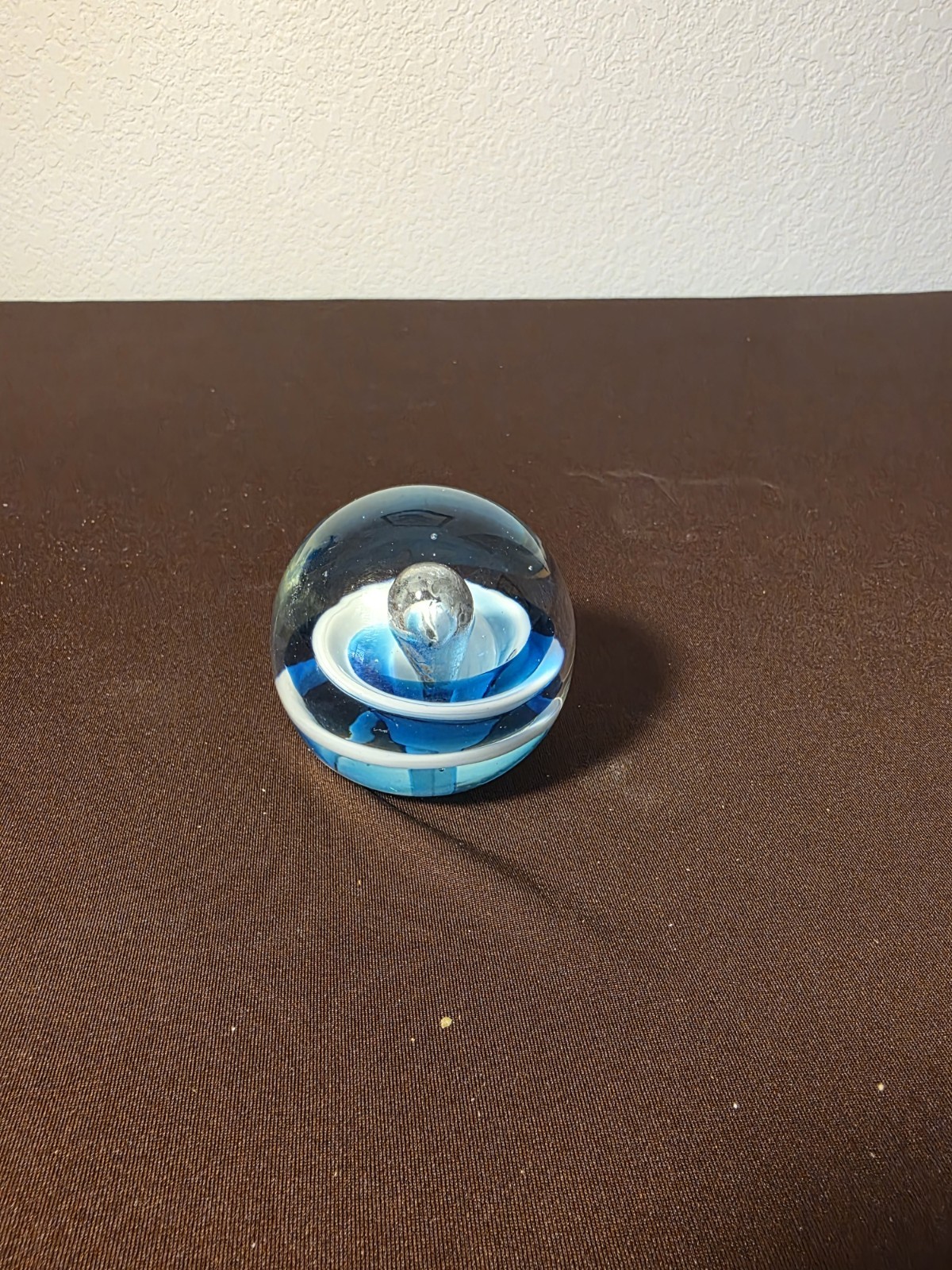Vintage studio art glass paperweight featuring blue, white swirls in a clear orb