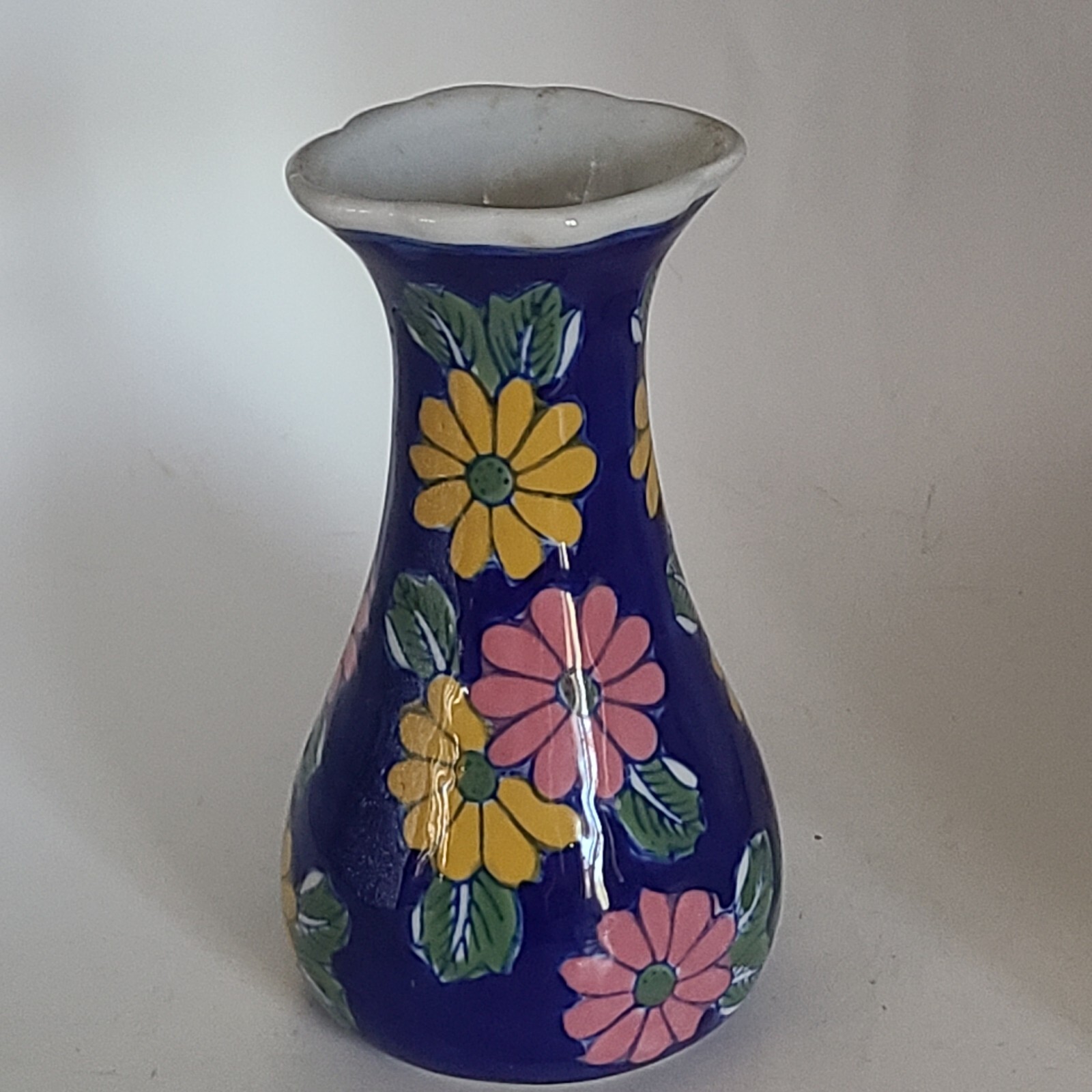 Vase in florals w blue. Pink and yellow florals. China. Scalloped opening.